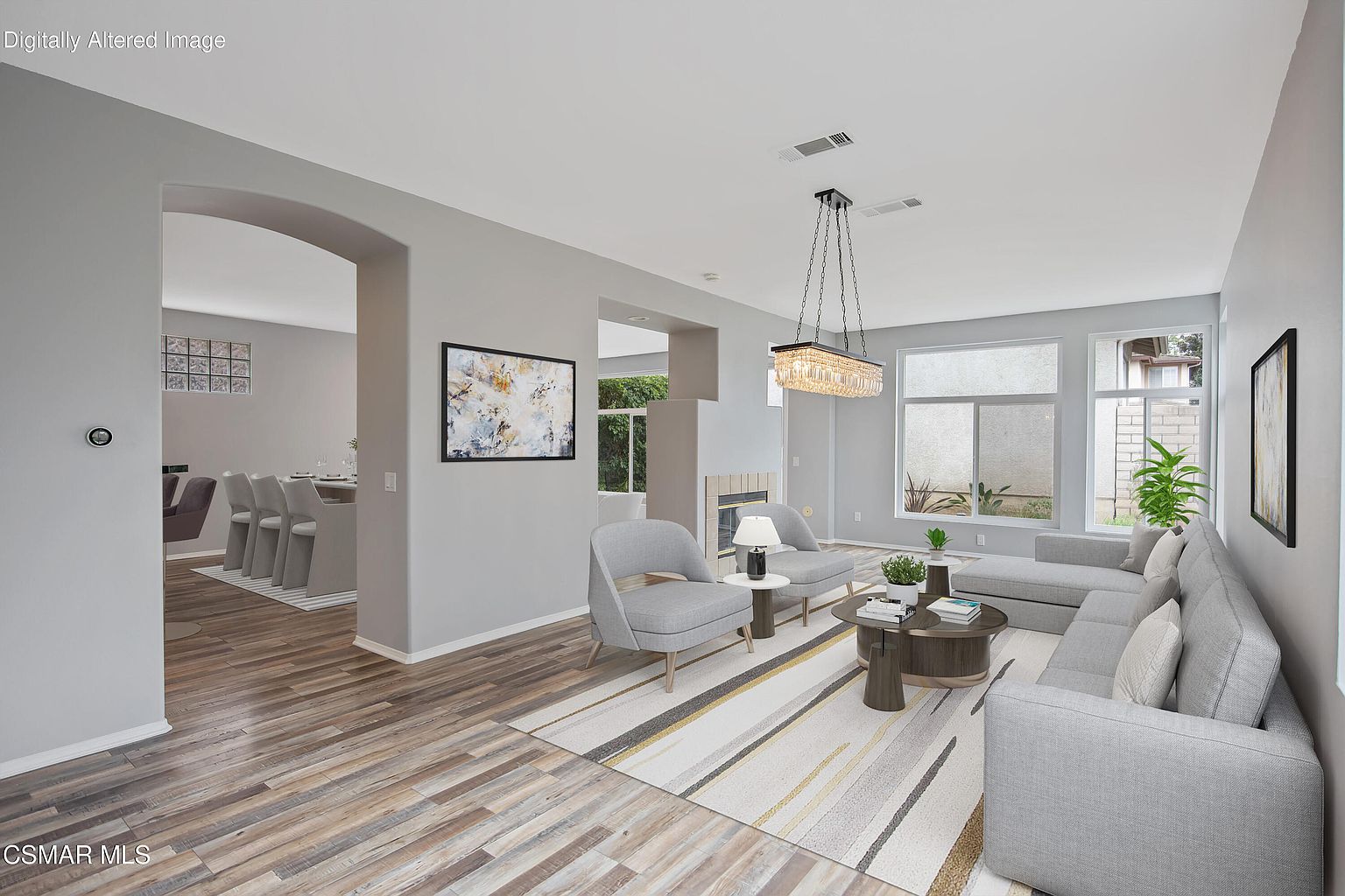 Open great room with plank flooring, linear chandelier, and fireplace.