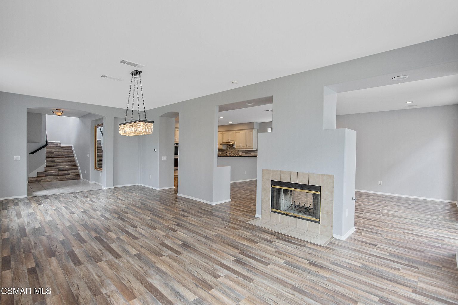 Living room with arched entry, fireplace, and plank flooring.